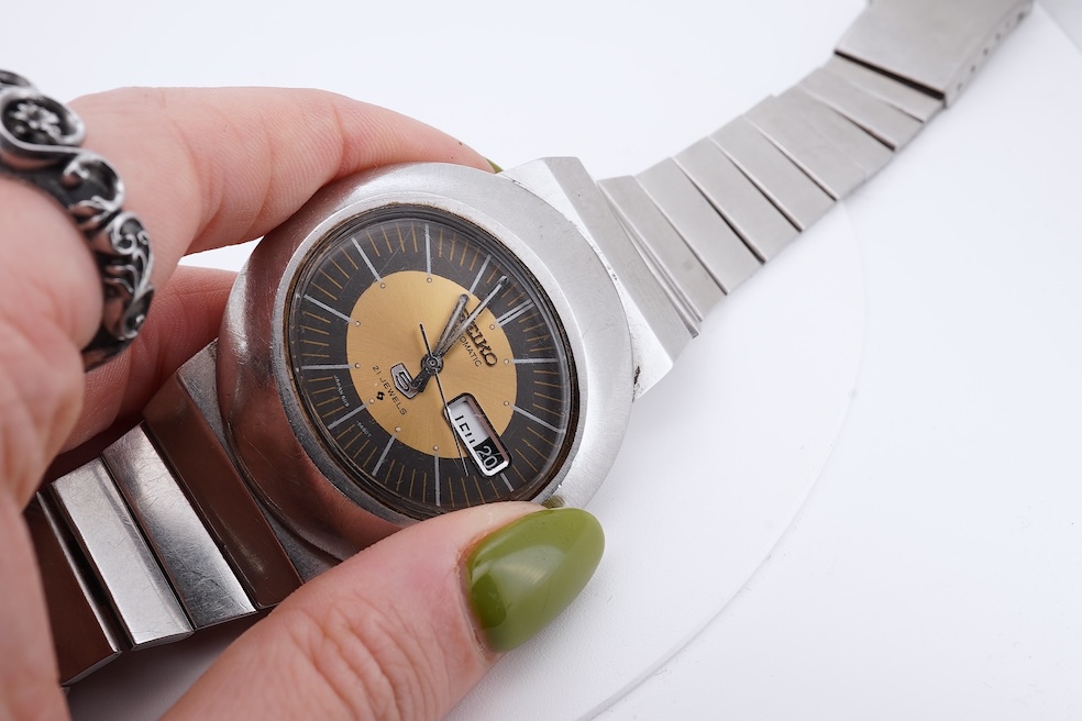 A gentleman's steel Seiko 5 Automatic wrist watch, with oval dial, baton numerals and date aperture, case diameter 40mm, case back numbered 228258, on a stainless steel Seiko bracelet(a.f.), no box or papers. Condition -
